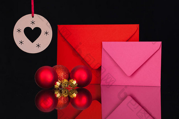 红色和粉色信封以及黑色玻璃桌上的圣诞装饰