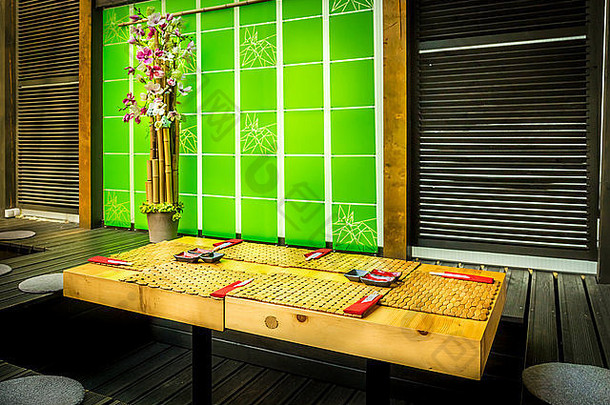 舒适的寿司餐厅，木质餐桌和绿色装饰墙