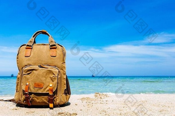 海边沙滩上的时尚棕色背包。旅游的概念，海上度假。水平框架、空间、可用空间。蓝天与wh