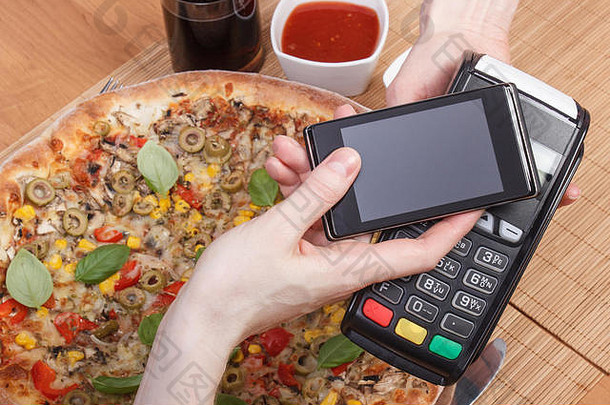 使用具有NFC技术的支付终端和移动电话，在餐厅、金融中心无现金支付素食比萨饼