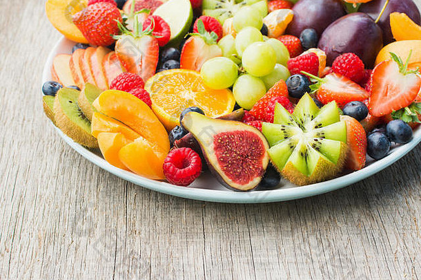 健康水果和浆果拼盘、草莓、覆盆子、橙子、李子、苹果、猕猴桃、葡萄、蓝莓摆在灰色木桌上、特写、空间