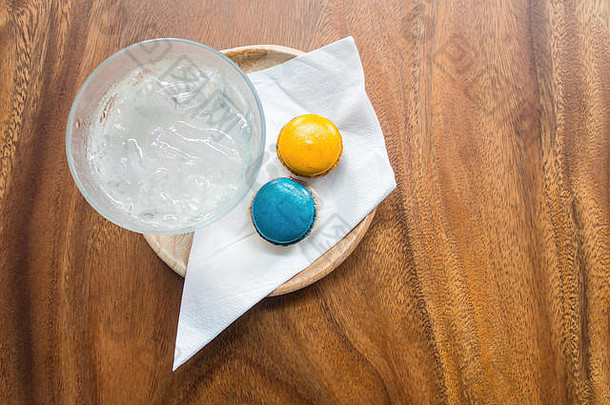 欢迎饮料<strong>套装</strong>，配有新鲜冰水、蓝色和橙色马加龙和白色海棉，装在木桌上的木制托<strong>盘</strong>中。