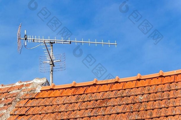 红色屋顶上的旧电视天线。接收电视。旧技术传播。