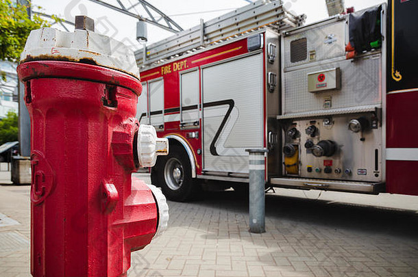 一个红色的<strong>消防</strong>栓在一辆大型红色<strong>消防</strong>车前面，可以看到水管附件的管道。