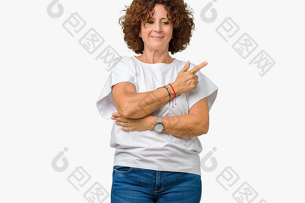美丽的中年老妇人，穿着白色t恤衫，在孤立的背景下用手指头指向展示广告的一侧，<strong>严肃认真</strong>
