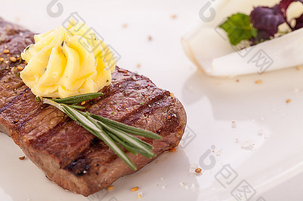 美味的烤牛肉牛排超过能转旋钮黄油用钉子钉上新鲜的迷迭香服务白色板关闭视图