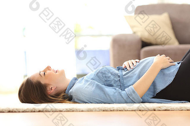 一名孕妇在家中客厅的地板上休息的侧视图