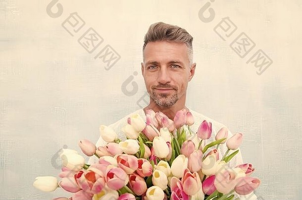 快乐女人的一天特殊的男人。郁金香花束英俊的的家伙持有粉红色的花有吸引力的男人。花男人。携带礼物情人节一天生日庆祝活动花商店