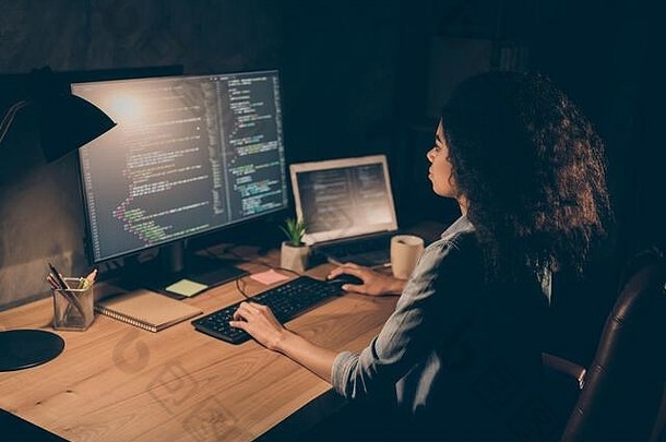 集中熟练的非洲式发型美国女孩it专家自由职业者企业家坐桌子上表格工作电脑使启动网络设计算法晚上