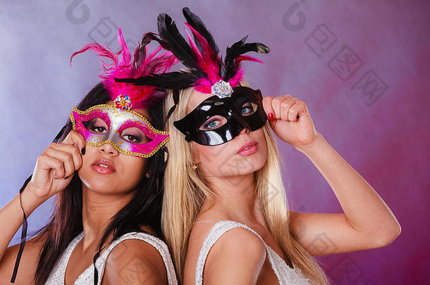 节日、人和庆祝的概念。在节日背景下，两名妇女戴着狂欢节威尼斯面具，混血白人。