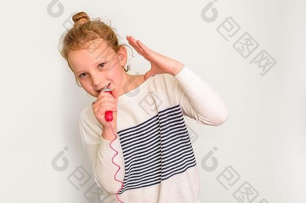 小梅洛曼女孩聆听喜爱的播放列表的照片声音优美，手持麦克风唱歌，穿着休闲服装，背景为白色。单色