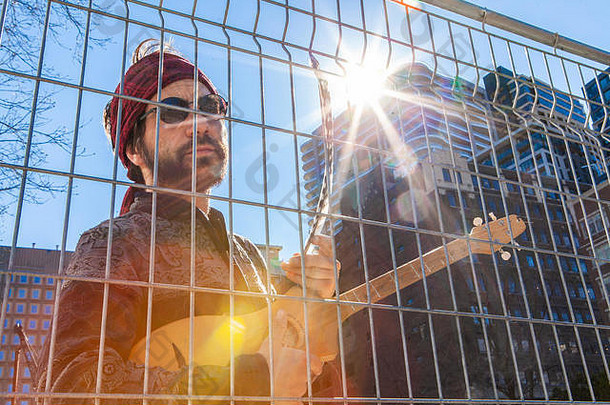 三十波西米亚的家伙查看特写镜头链链接障碍市中心持有吉他羽毛明亮的太阳眩光高上升