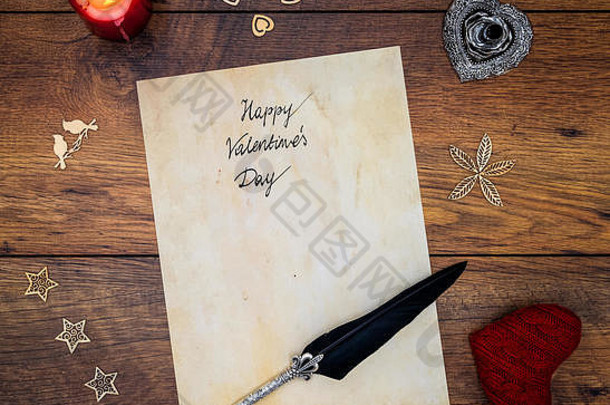 经典的情人节快乐卡片手写在羊皮纸上红色拥抱之心红色蜡烛装饰银色羽毛笔和复古橡木顶视图