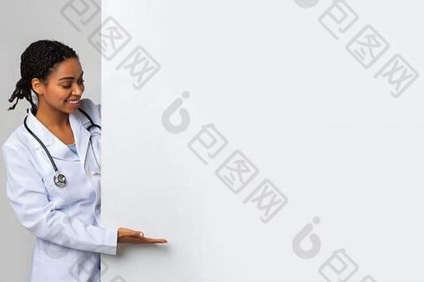 黑人女医生看着并指着空白的大广告牌