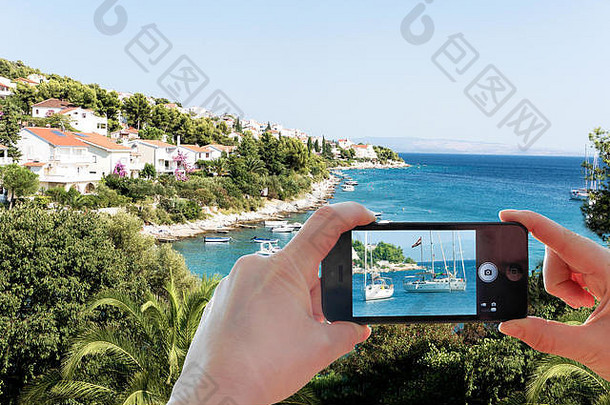 用智能手机拍摄克罗地亚海岸景观和亚得里亚海。屏幕上的照片和背景中如画的风景。