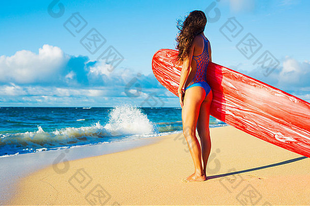 日落时海滩上美丽的冲浪女孩。夏日乐趣户外生活方式。