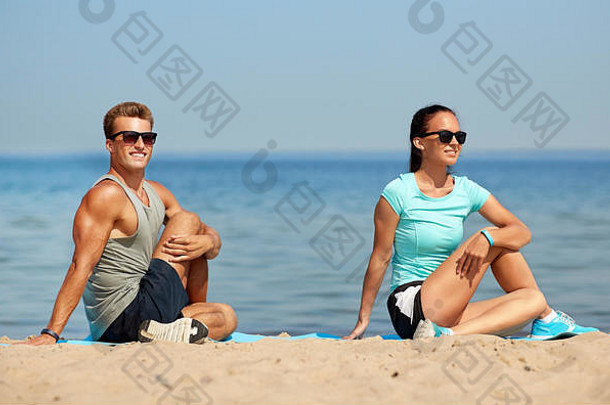 微笑的夫妇在海滩上伸展双腿