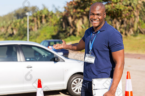 开朗的年轻非洲驾驶教练介绍一辆汽车