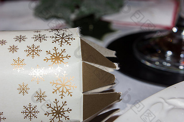 把圣诞饼干放在桌子上，上面有一块圣诞桌布，背景是一个酒杯的一部分。