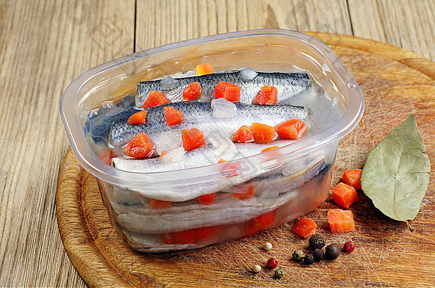 将腌制过的咸鱼和胡萝卜放在厨房板上打开的罐子里