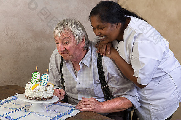 老人在养老院吹灭生日蛋糕上的蜡烛