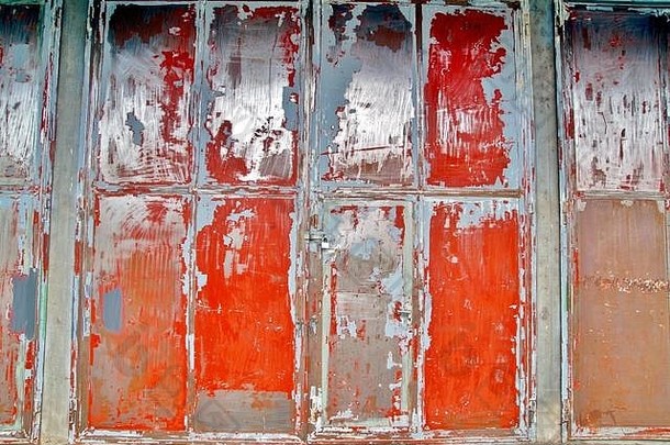 一座旧工业建筑的框架型<strong>钢立面</strong>。一栋厂房的旧墙上有裂缝的旧油漆。旧的红色金属门。