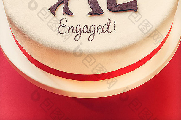红色背景上的白色圆形蛋糕，顶部装饰着糖的男女轮廓。