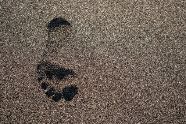 西班牙加那利群岛特内里费，黑暗火山海滩沙滩上的足迹，阳光普照