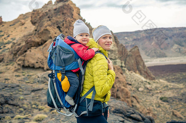 一家人徒步旅行，小男孩坐在妈背包里旅行。带着孩子在山区进行秋季家庭旅行。婴儿ca度假之旅
