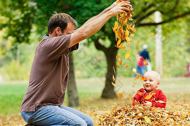 爸爸把树叶洒在小女儿身上。