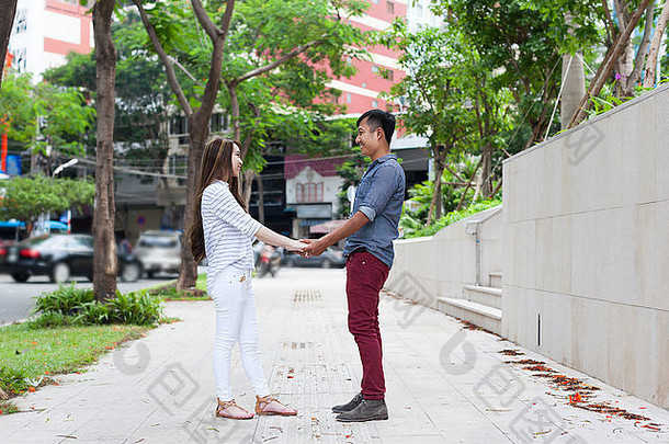 亚洲夫妇手牵着手，面带微笑，期待着面对约会