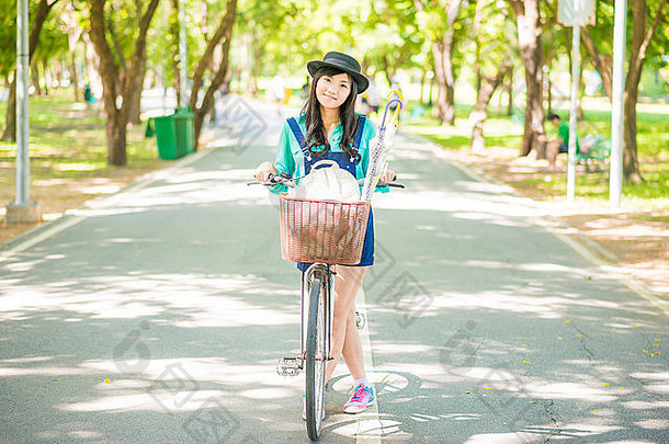在夏季公园骑自行车的亚洲年轻女子。户外活动的人。