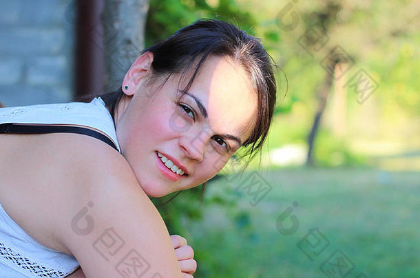 美丽微笑的年轻女孩倚在草地上