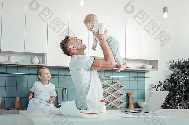 快乐可爱的父亲站着抱着一个婴儿。