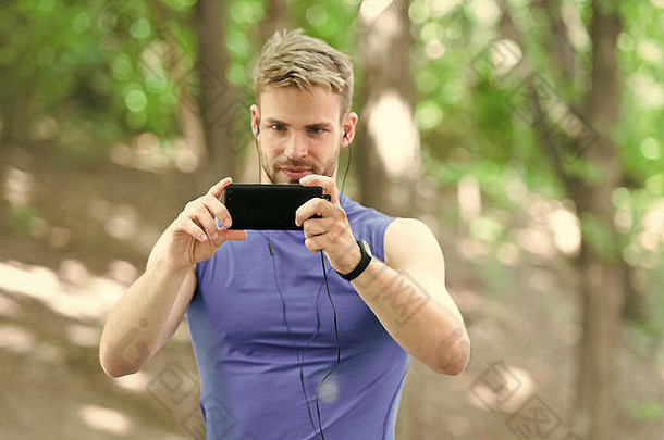 男人。运动员集中脸智能手机照片自然背景运动员培训计步器耳机小工具运动员猪鬃健身跟踪器智能手机捕获愉快的时刻