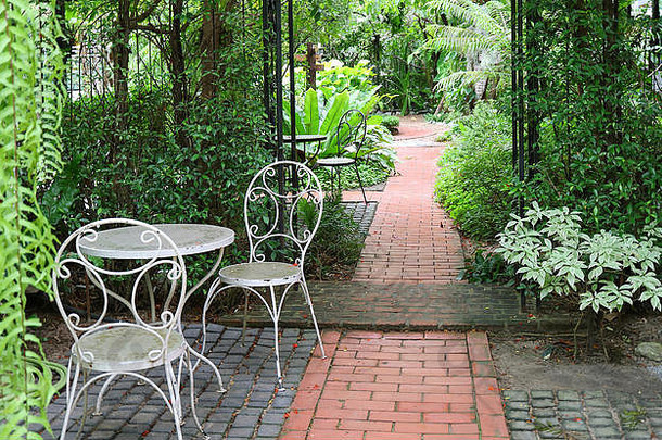 热带花园白色熟铁桌椅，砖砌人行道
