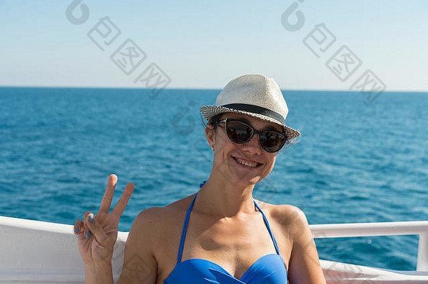 一位快乐的中年妇女坐在游艇上，背景是大海。