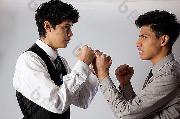 英俊、年轻、西班牙裔的兄弟，穿着商务装，举起拳头准备打架