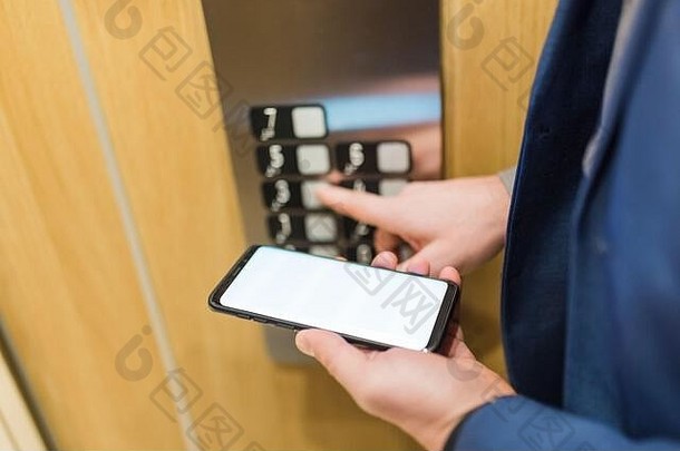 男子在使用电梯控制面板时手拿着黑屏<strong>手机</strong>。