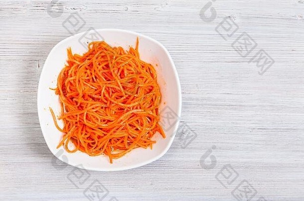 灰色木质背景上的碗中韩式胡萝卜（高丽沙拉、辣味腌制胡萝卜）顶视图，带有文字空间