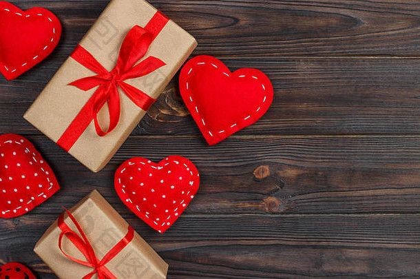 木制背景上有红色丝带的心形和礼品盒。