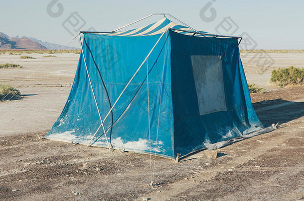 旧的泥泞的蓝色露营帐篷在博纳维尔盐滩的沙漠中。