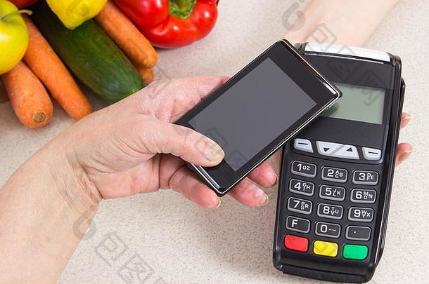 老年妇女使用带有NFC技术的<strong>手机支付</strong>终端的手，无现金<strong>支付</strong>购物、水果