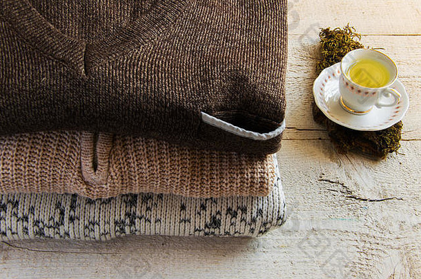 舒适温暖的maxi针织毛衣和一杯茶，木质背景，并留有文字空间。概念-时尚、舒适的家居生活
