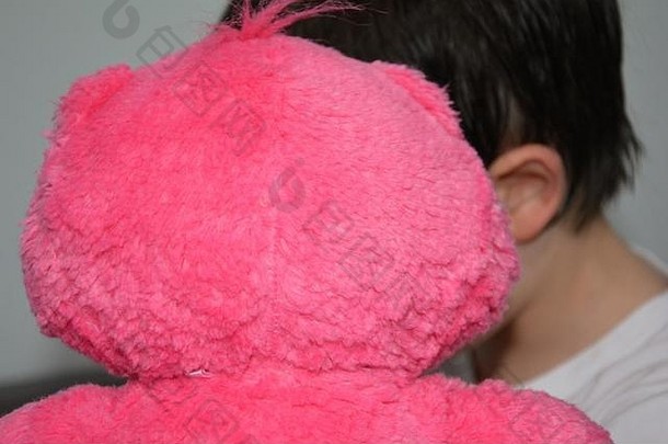 一个孩子带着他的粉色泰迪熊
