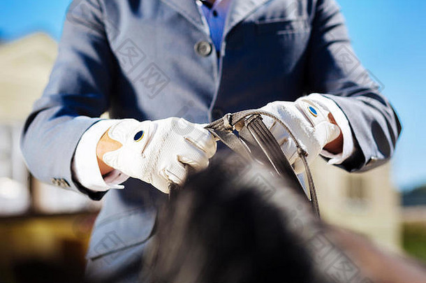 运动员穿蓝色的手套准备好了马骑