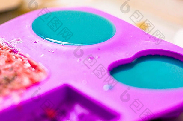 蓝色肥皂在各种形状的紫色硅模具中设置