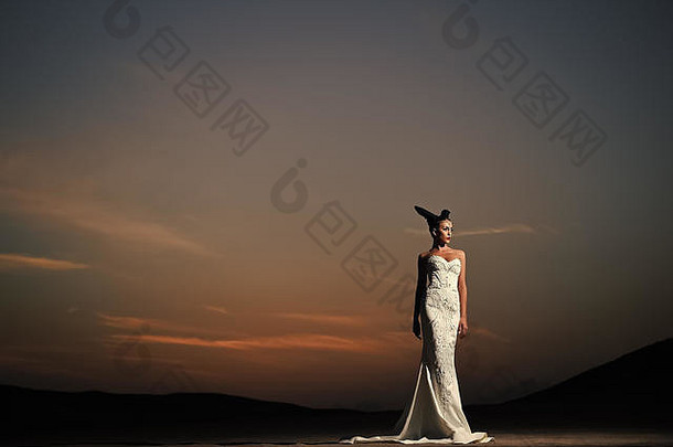 日落时穿着白色婚纱的女人。在夜空中穿着户外服装的女孩。新娘和仪式。婚礼时尚美容院。优雅时尚的模特。
