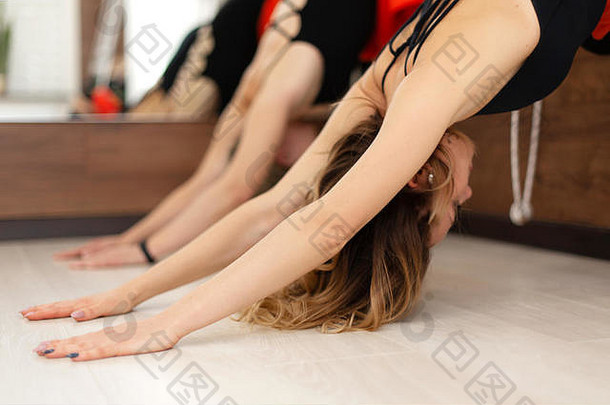 在健身房伸展绳索练习瑜伽的女人。健康的生活方式。