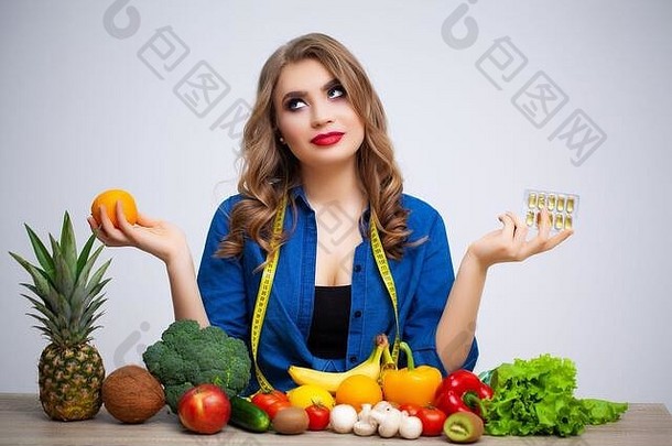 桌子旁的女人拿着橘子和水果蔬菜上的药丸